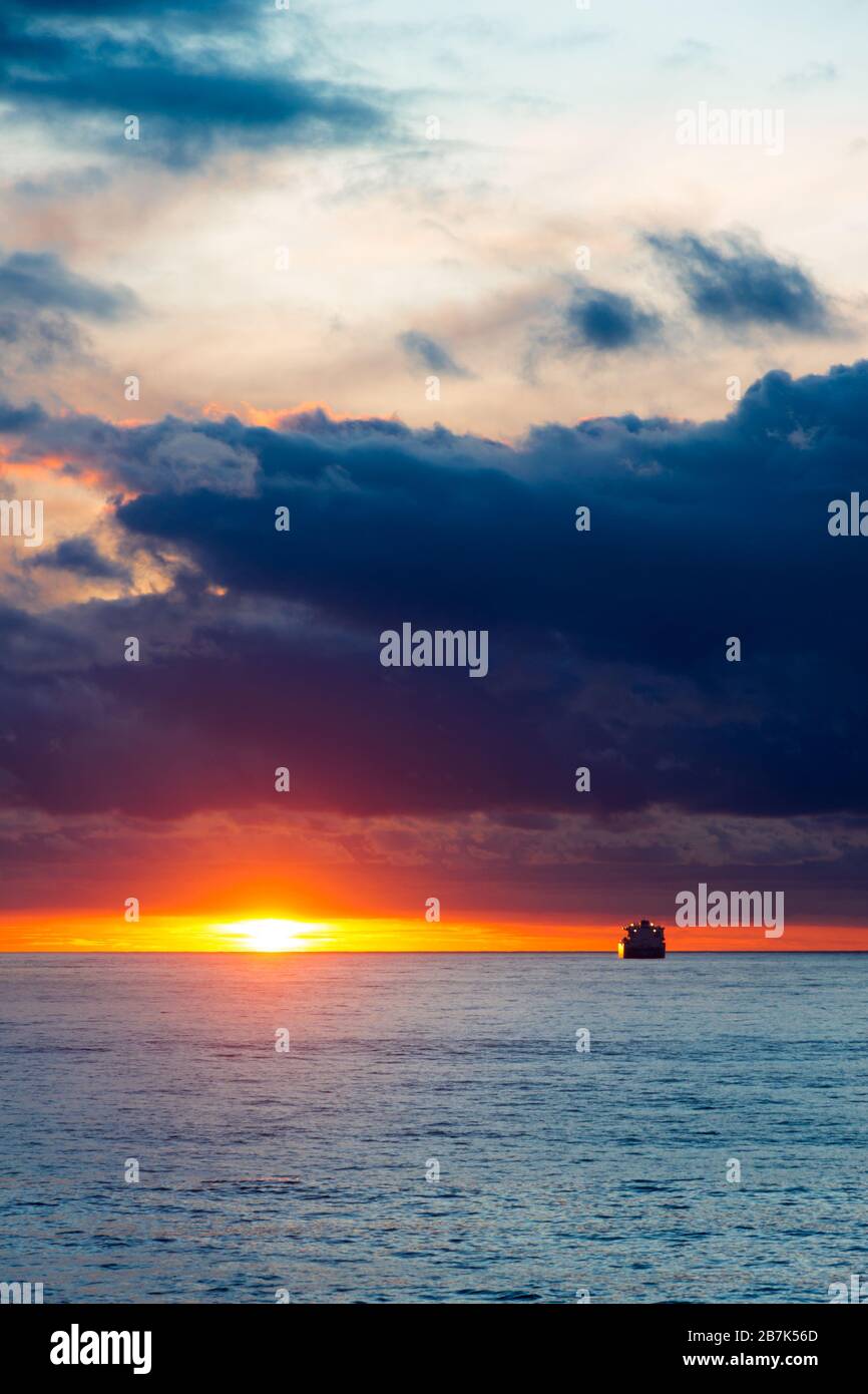 Sea sunset landscape with cloud  sun reflection and ship on the horizon Stock Photo