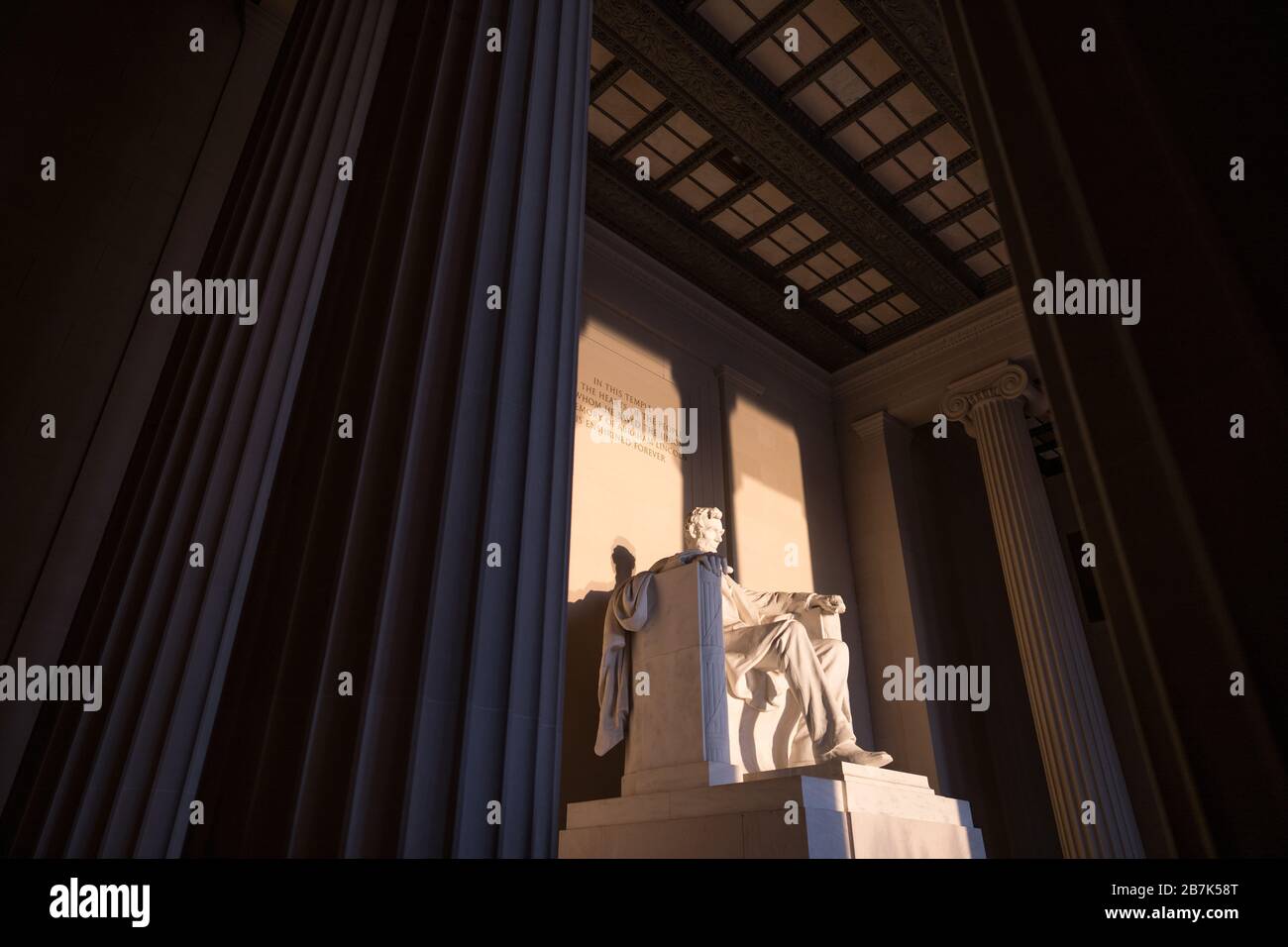 WASHINGTON DC, USA - The large statue inside the Lincoln Memorial's main chamber catching the early morning golden sunlight at sunrise during the fall (autumn) equinox. The Lincoln Memorial sits on the western end of the Reflecting Pool and faces directly east. The statue is deep within the chamber and is normally well out of reach of directly sunlight. Stock Photo