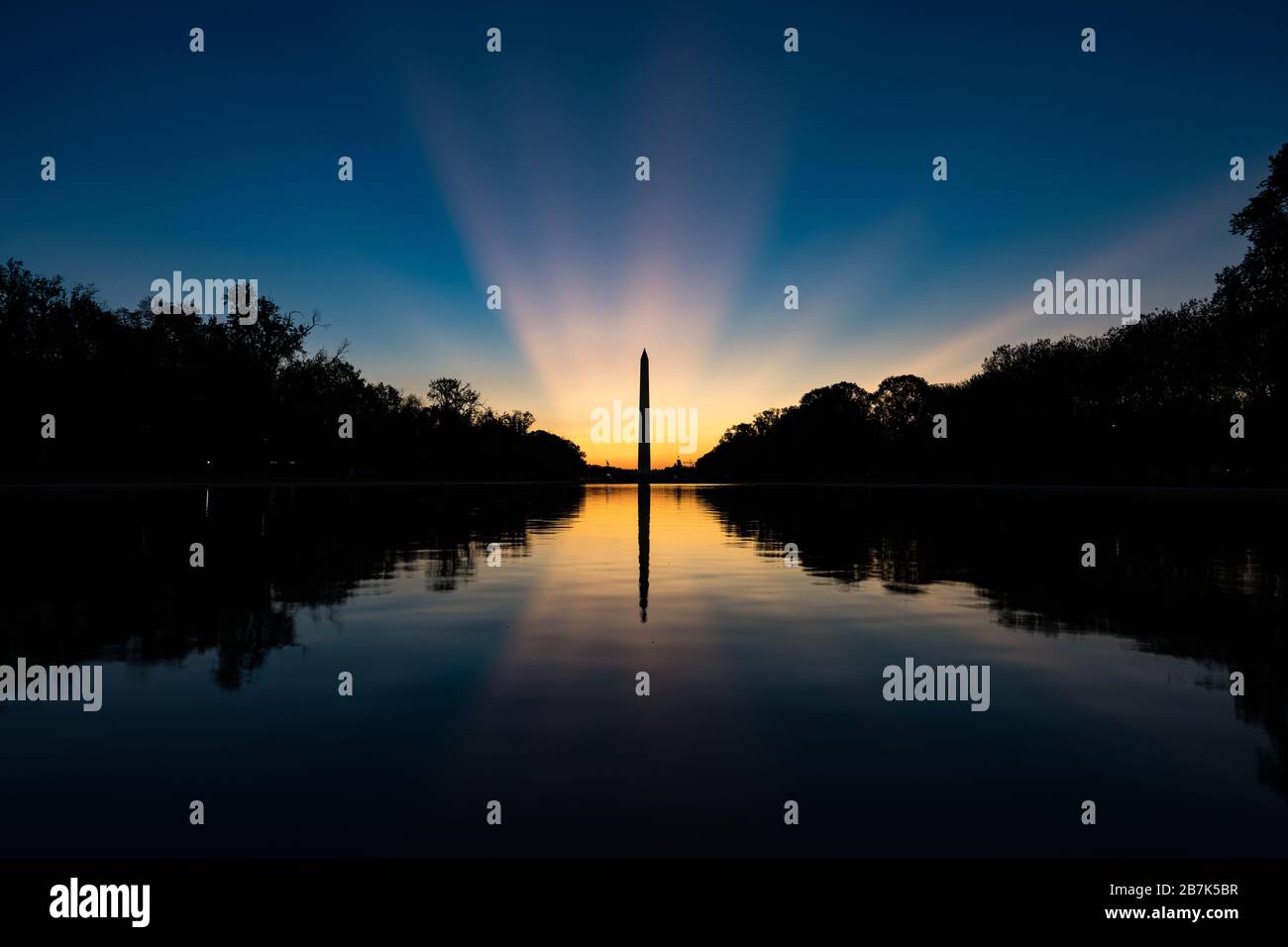 WASHINGTON DC, United States — Crepuscular rays appear behind the Washington Monument just before sunrise around the spring equinox in Washington DC. Stock Photo
