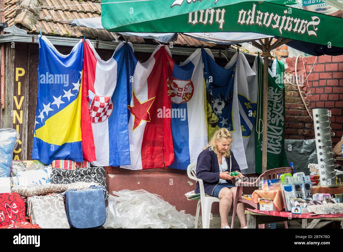 BRCKO, BOSNIA - JUNE 19, 2016: Flags of Bosnia and Herzegovina, Serbia, Croatia and Yugoslavia on display on a market in the district of Brcko, with i Stock Photo