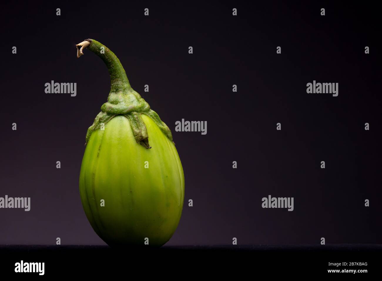 Vibrant green lot of scarlet eggplant vegetable grouped together on dark background Stock Photo