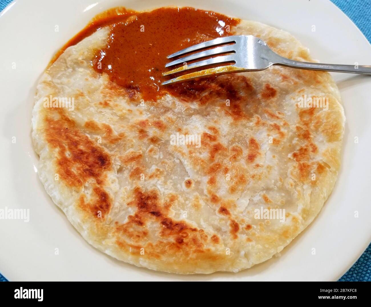 Malaysian fried pancake called Roti Canai with curry gravy and silver fork Stock Photo