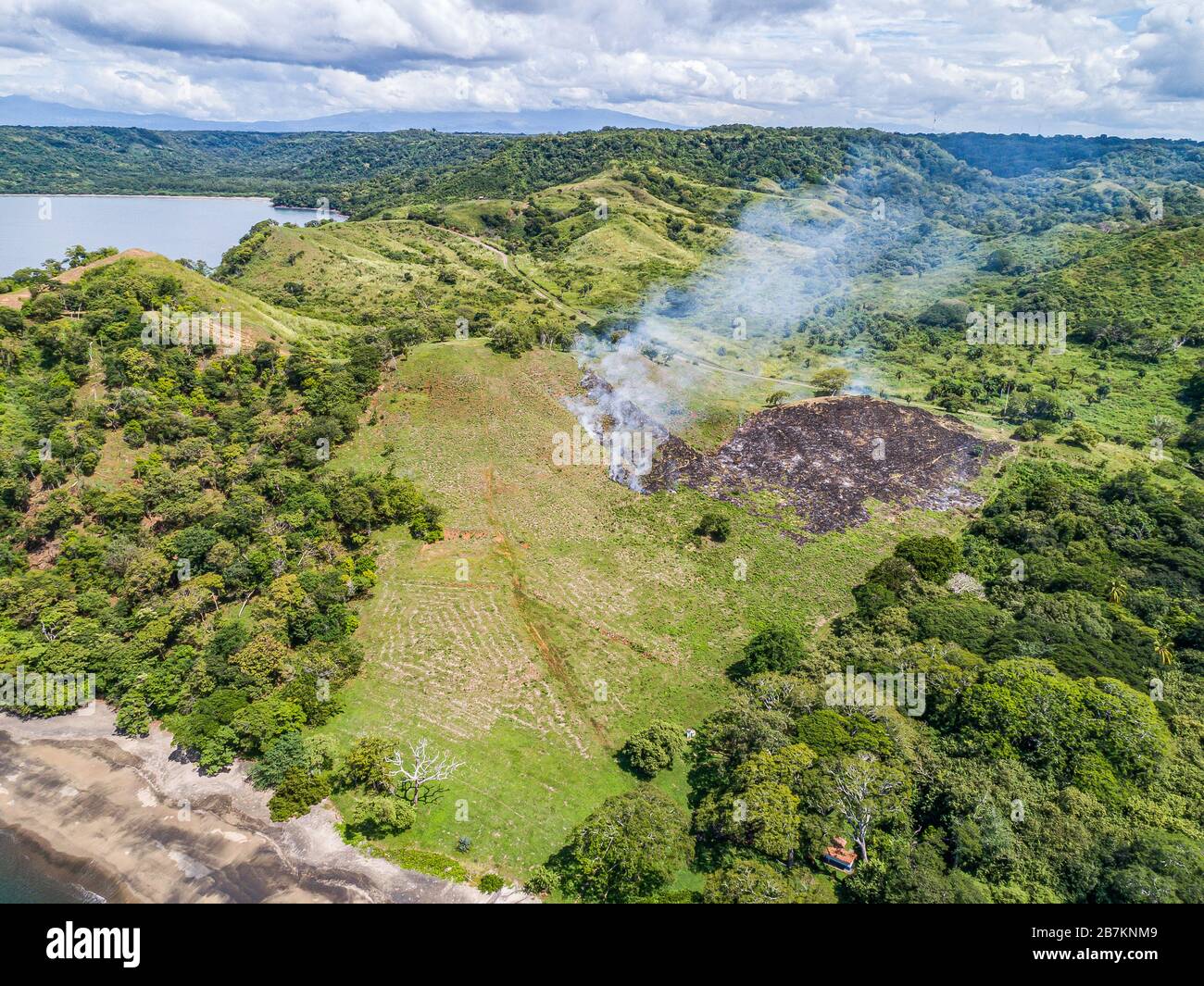 Aerial shot of small fire at the tropical coastline by Playa Arenillas in Costa Rica in peninsula Papagayo coast in guanacaste. Stock Photo