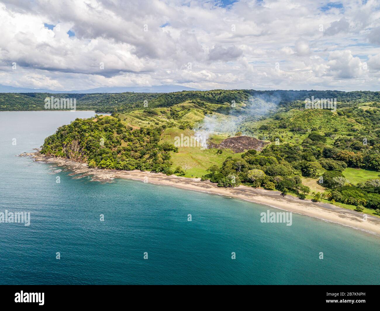 Aerial shot of small fire at the tropical coastline by Playa Arenillas in Costa Rica in peninsula Papagayo coast in guanacaste. Stock Photo