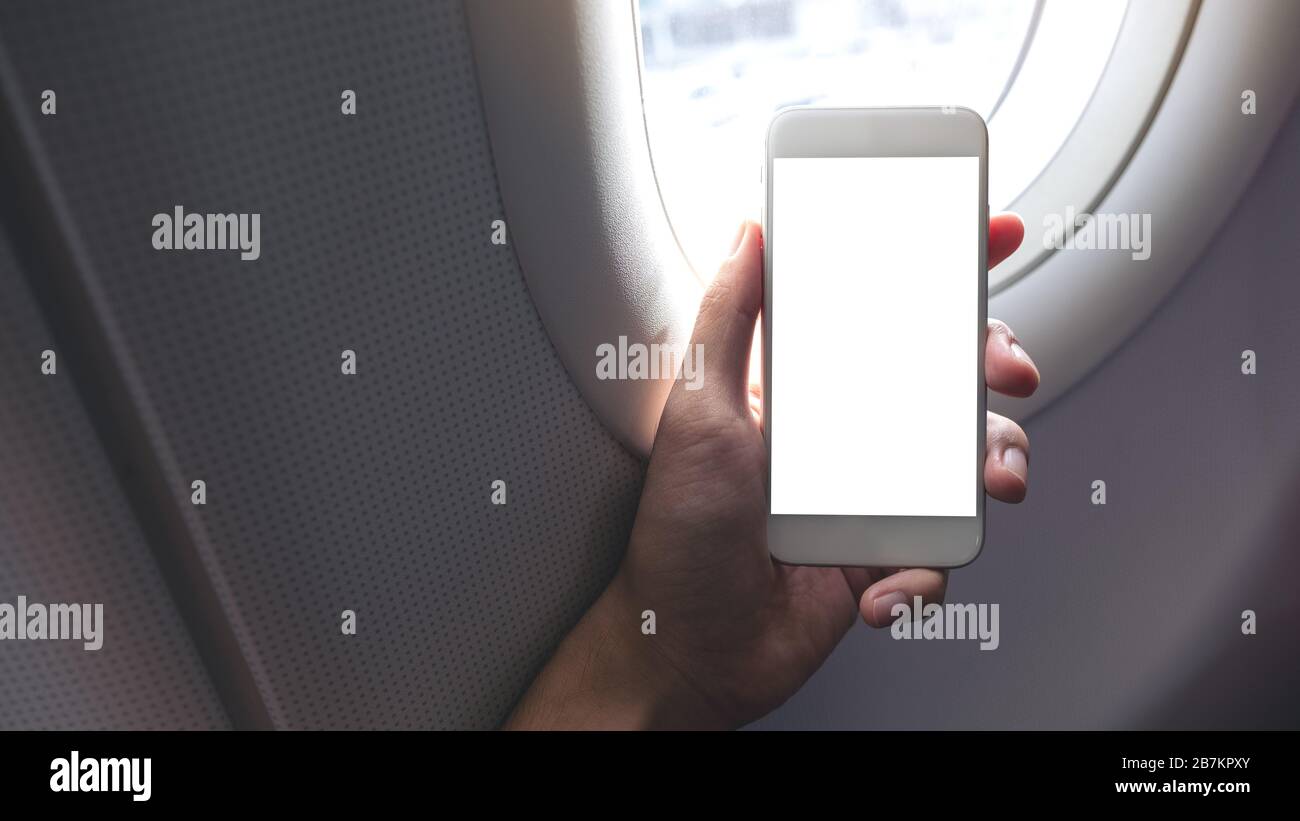 Download Mockup Image Of A Hand Holding A White Smart Phone With Blank Desktop Screen Next To An Airplane Window Stock Photo Alamy