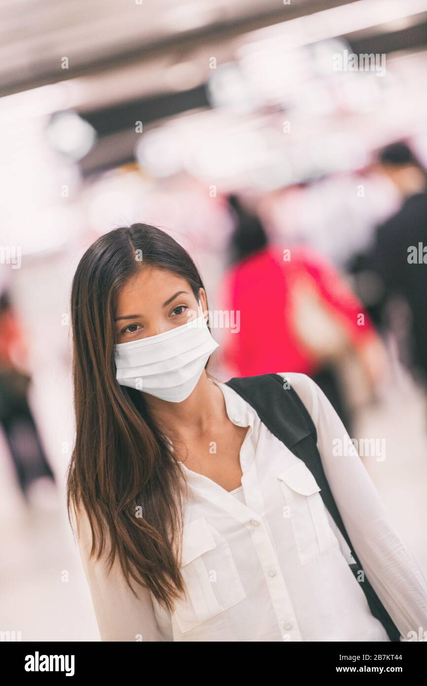 Virus mask Asian woman travel wearing face protection in prevention for coronavirus in China. Lady walking in public space bus station or airport. Stock Photo