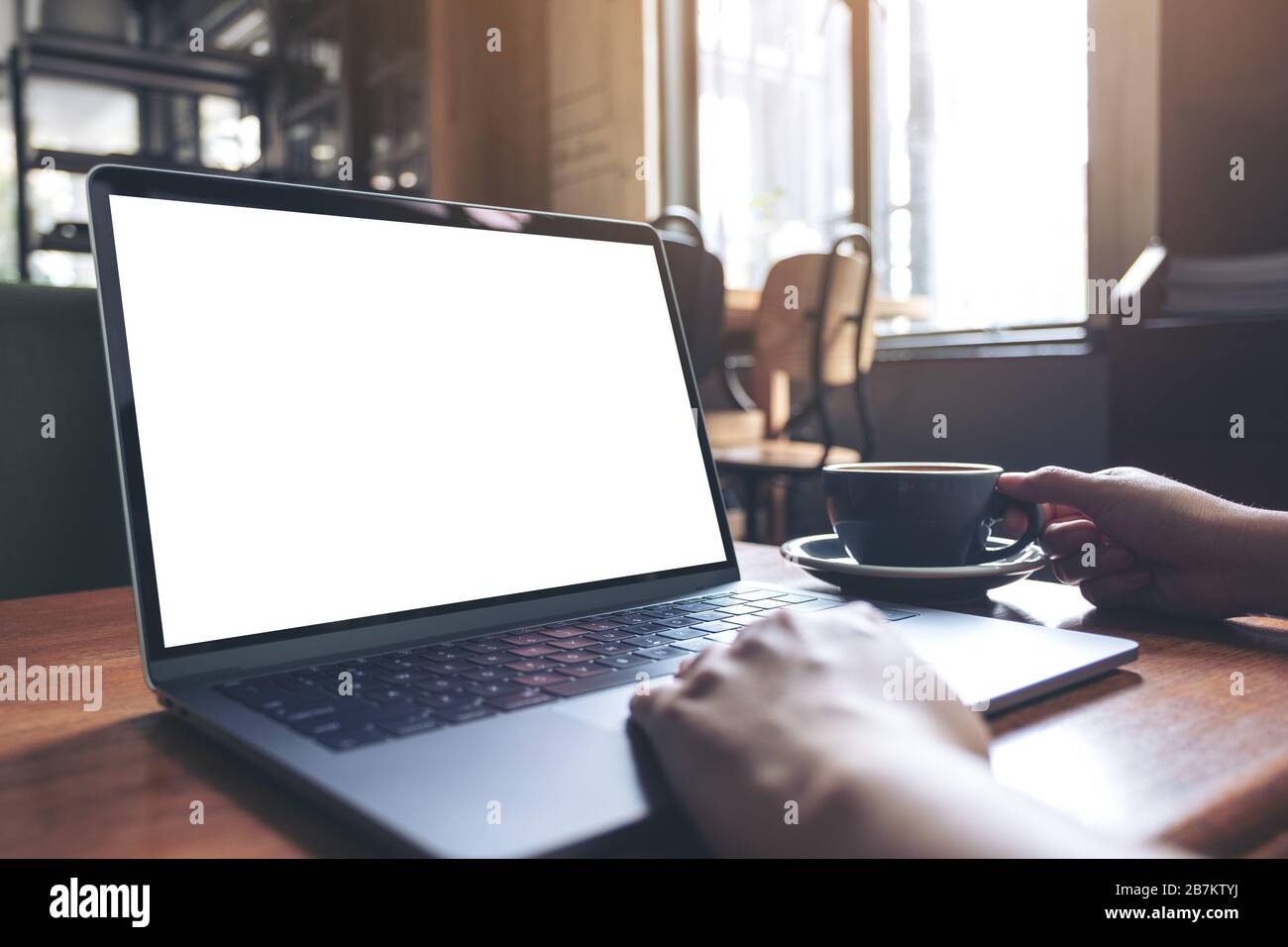 Mockup image of a woman using laptop with blank white desktop screen ...