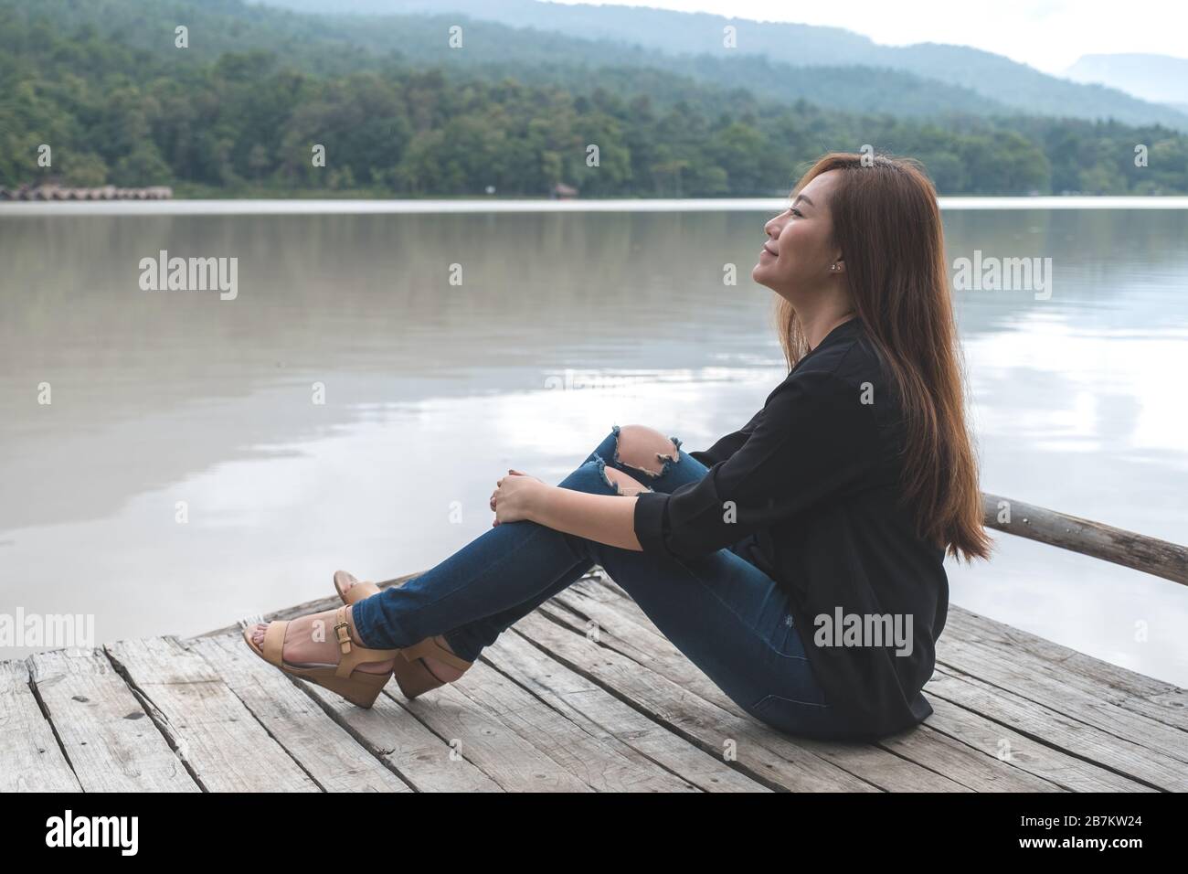 Closeup image of an asian woman sitting alone on an old wooden pier by ...