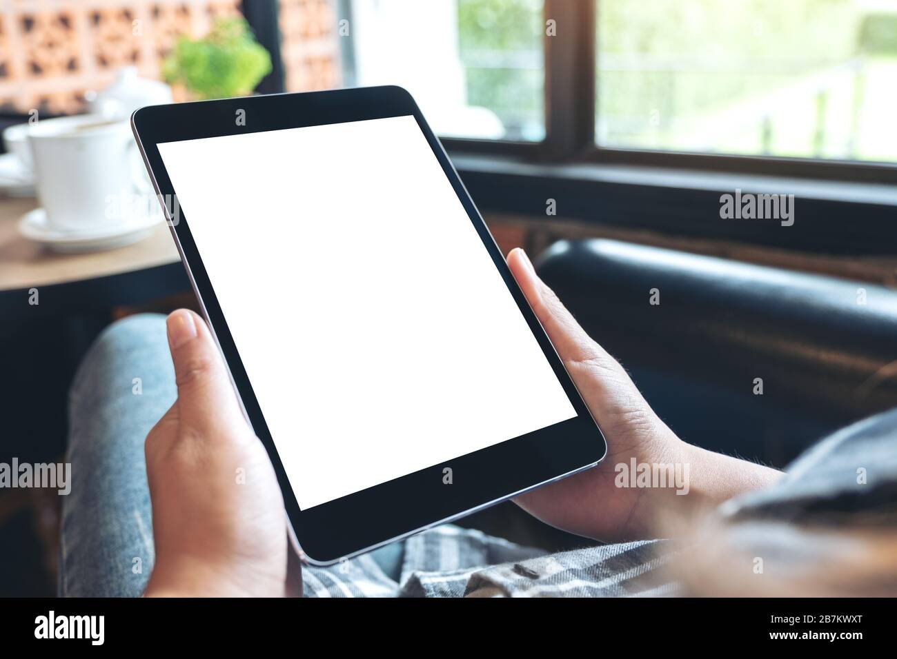 Mockup image of hands holding black tablet pc with blank white desktop ...