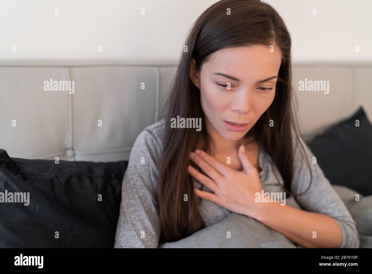 Coronavirus disease (COVID-19) Corona virus illness can be more severe for some people and can lead to pneumonia or breathing difficulties. Asian woman with shortness of breath sick at home. Stock Photo