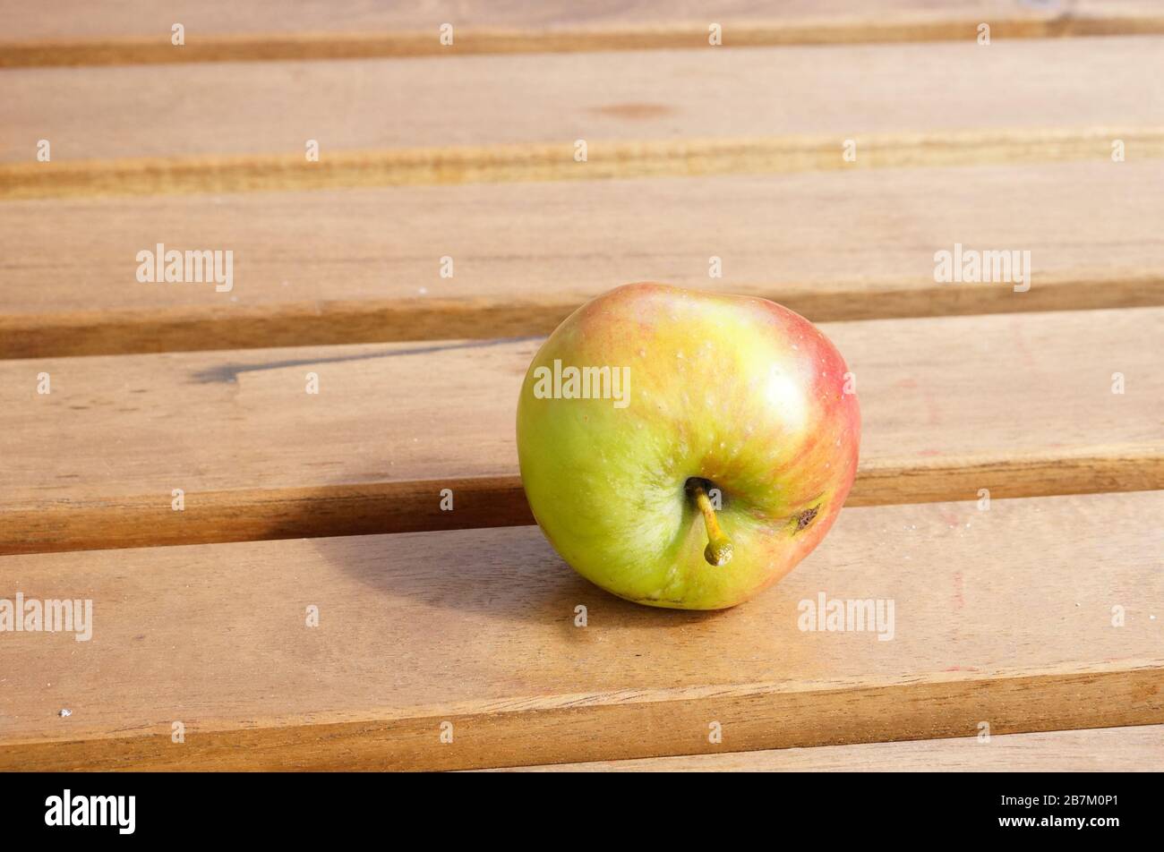 Closeup shot of a fresh apple on a wooden surface Stock Photo