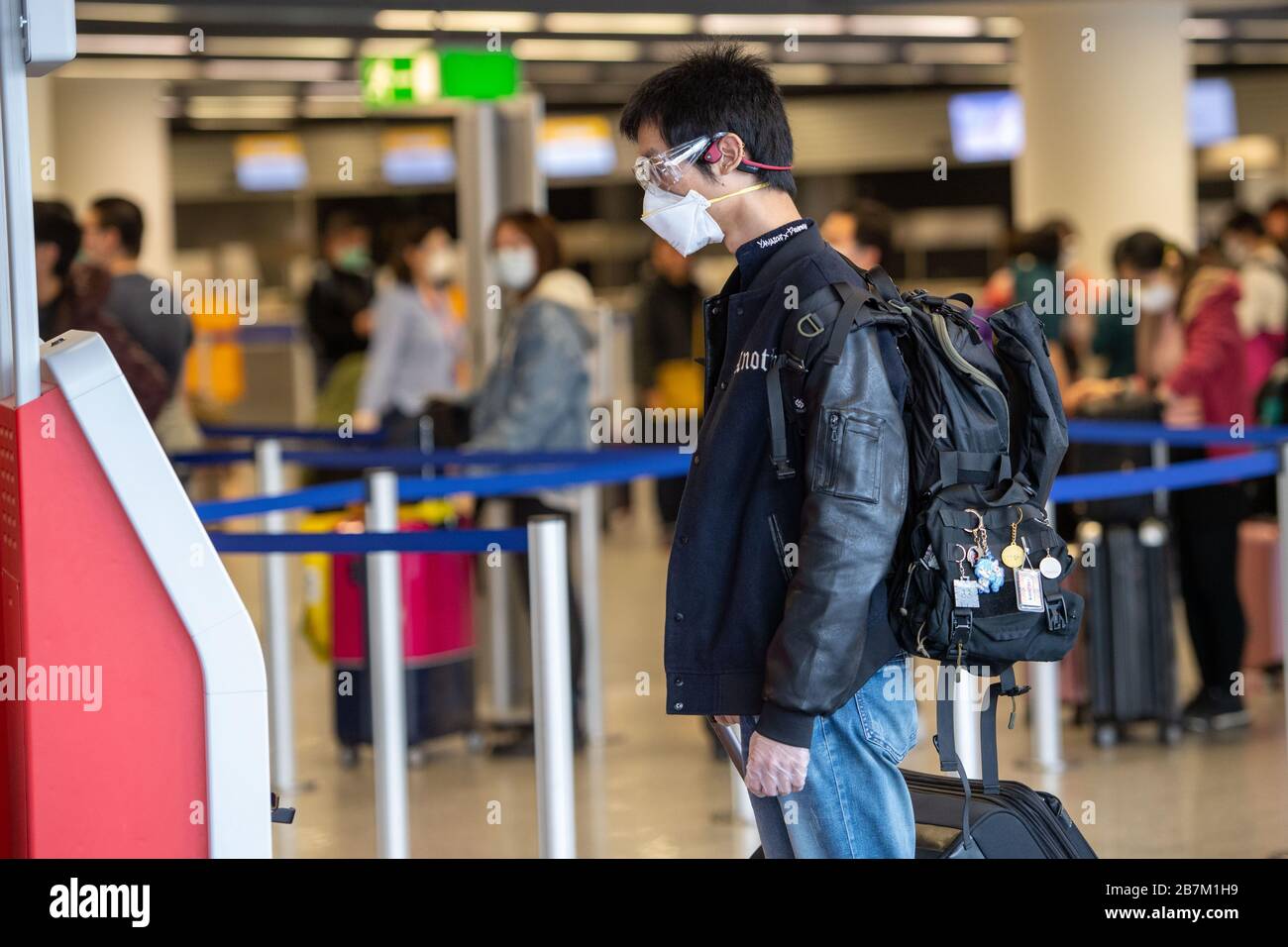 A passenger with face mask looks at a monitor, half figure, half figure, Frankfurt Airport