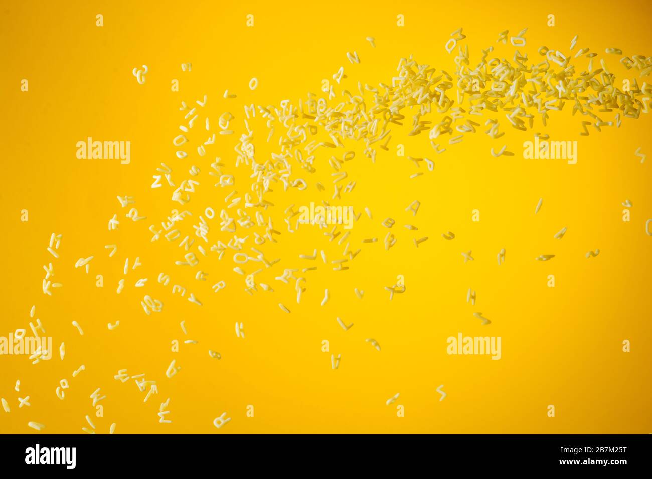 Concept of flying yellow raw italian pasta on yellow background with unfocused elements. Stock Photo