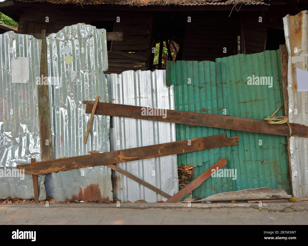 Closeup corrugated galvanized steel sheet fastened by wood bars used for preventing access to abandoned house Stock Photo