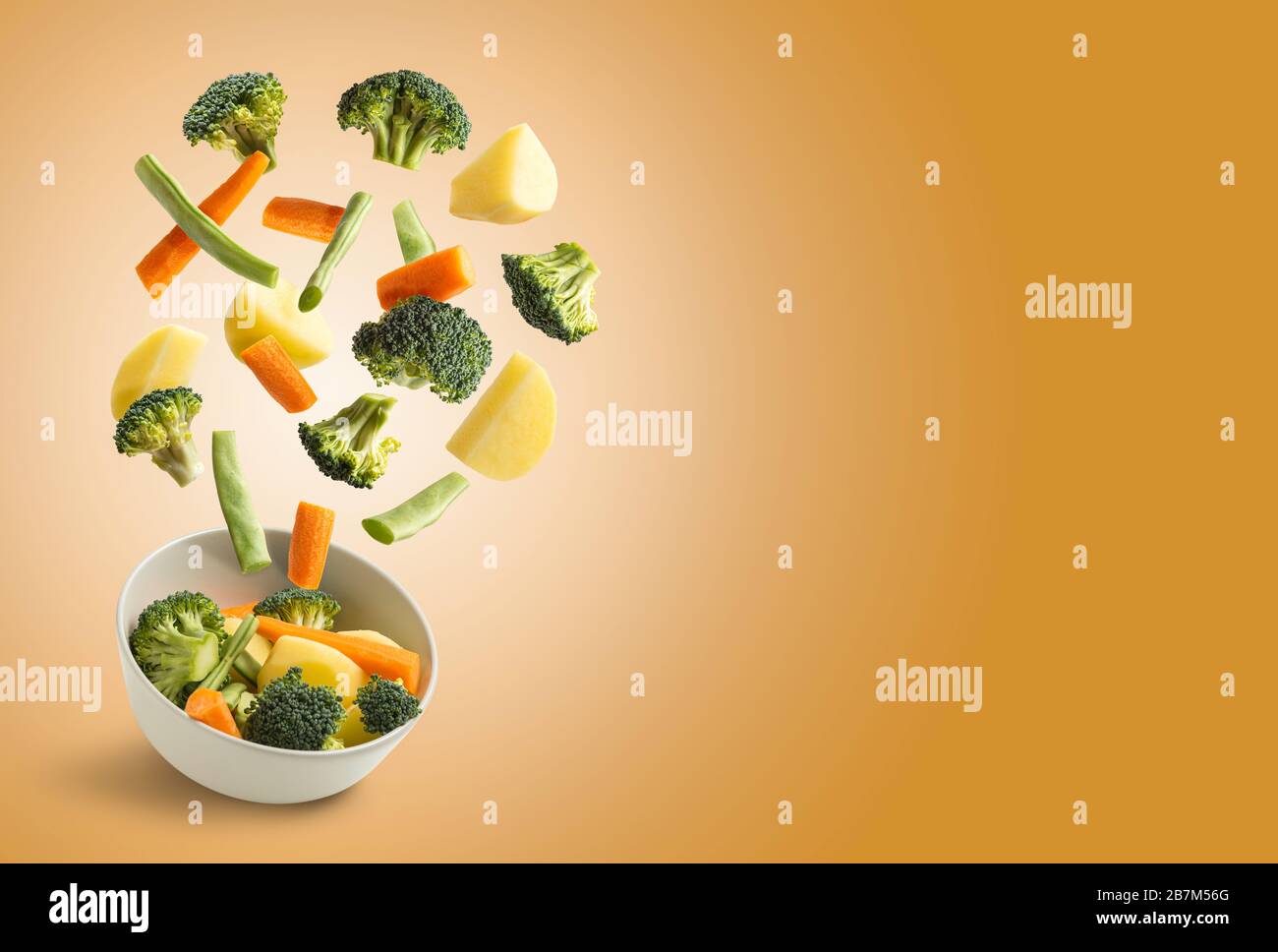 Boiled vegetables flying over orange with copy space, green beans, broccoli, potato, carrot Stock Photo