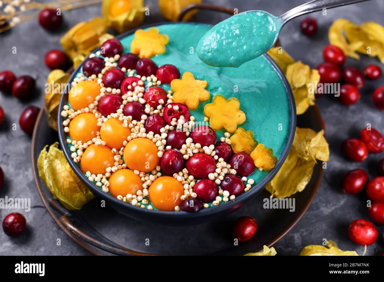 Blue fruit smoothie bowl dyed with healthy natural spirulina powder  decorated with cranberries, physalis and kaki fruits and puffed quinoa  grains Stock Photo - Alamy