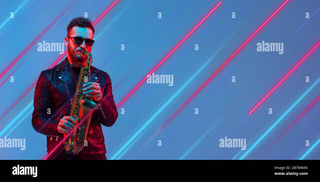Creative emotions and neon lines on blue background, flyer, proposal. Caucasian young musician playing saxophone. Concept of human emotions, facial expression, sales, ad, music, hobby. Modern art. Stock Photo