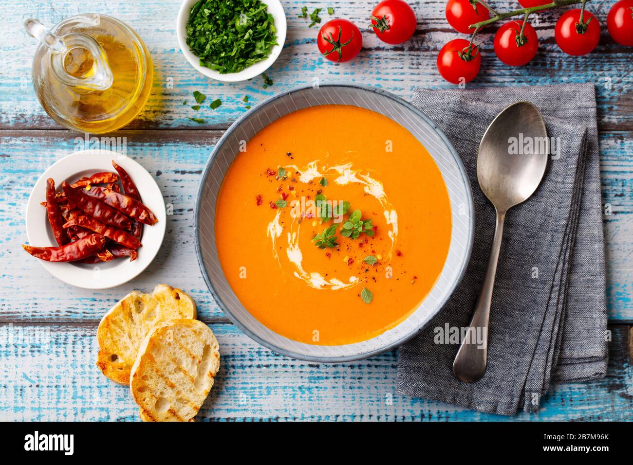 Pumpkin cream soup with fresh herbs in a bowl. Blue wooden background. Top view. Stock Photo