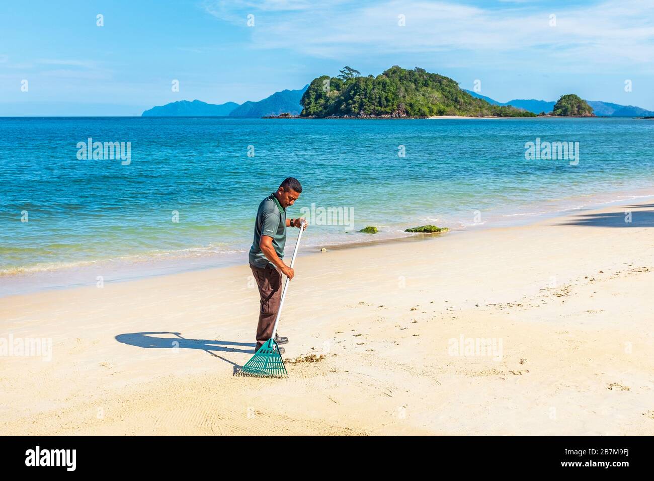 Man raking and cleaning the beach at Andaman, Langkawi, Malaysia, Asia Stock Photo