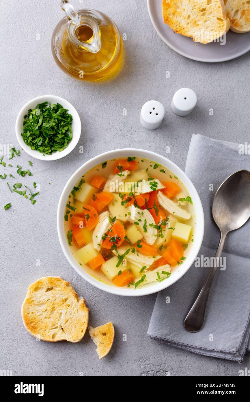 Chicken soup with vegetables in white bowl. Grey background. Top view. Stock Photo