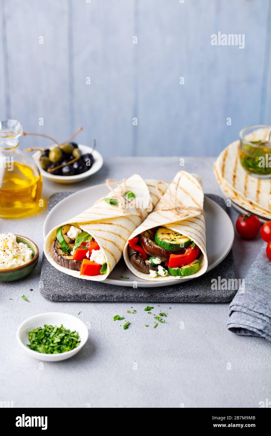 Wrap sandwich with grilled vegetables and feta cheese on a plate. Grey background. Copy space. Stock Photo