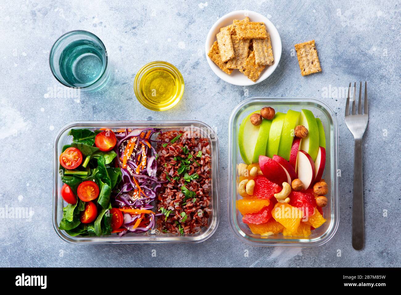 Lunch box with vegetables, brown rice and fruits salad. Healthy eating. Grey background. Top view. Stock Photo