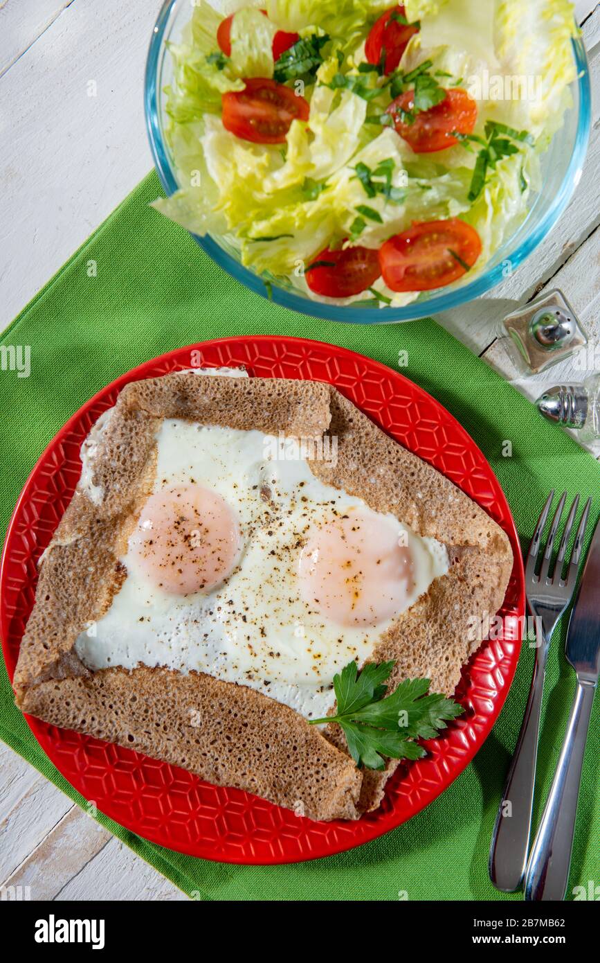 homemade Breton crepe with egg in a red plate Stock Photo