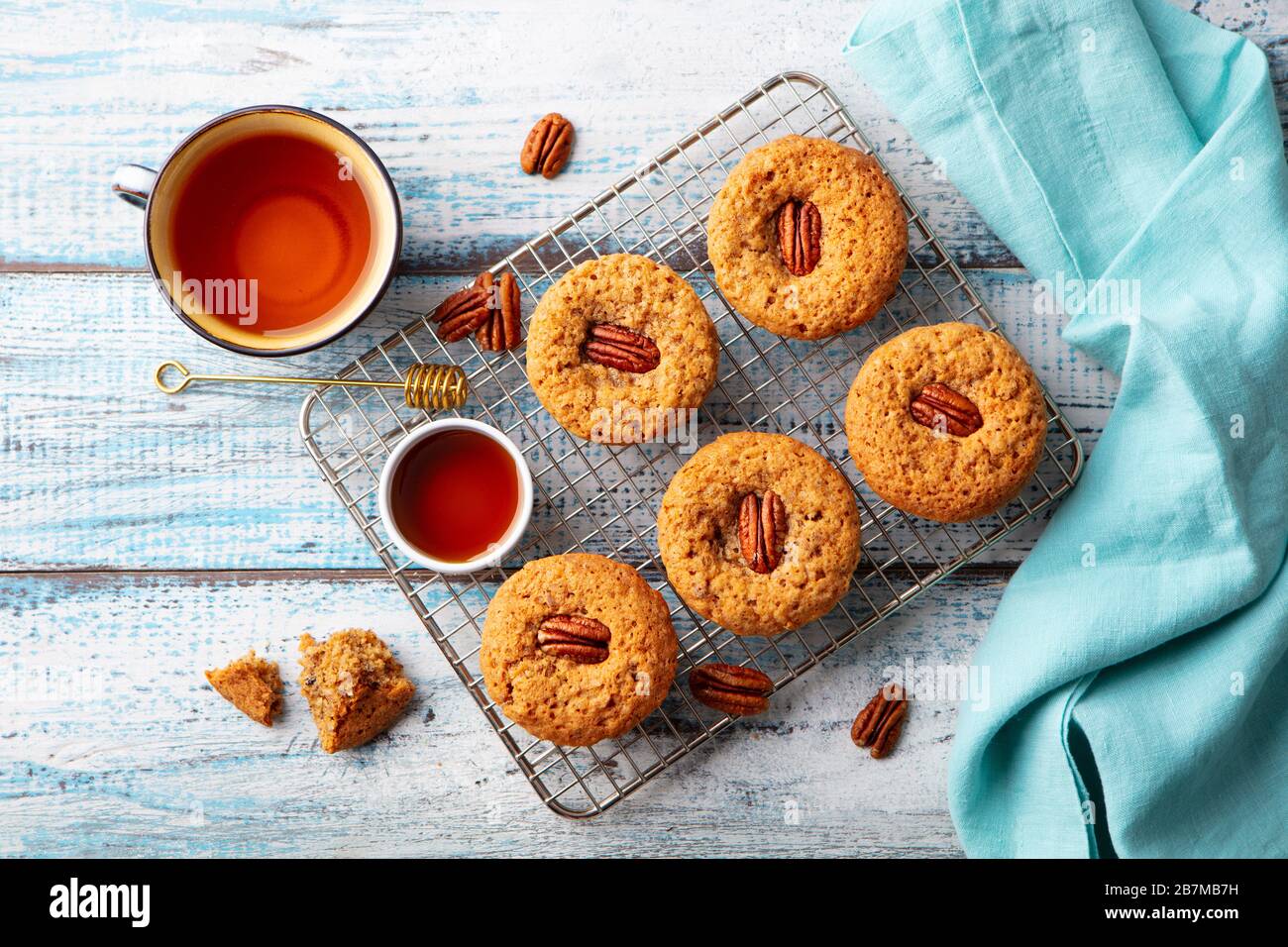 Pecan nut muffins on cooling rack with a cup of tea. Blue wooden background. Top view. Stock Photo