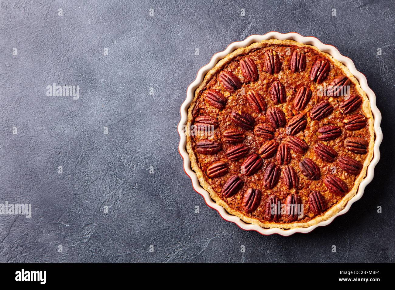 Pecan nut pie, tart in baking dish. Grey background. Copy space. Top view. Stock Photo