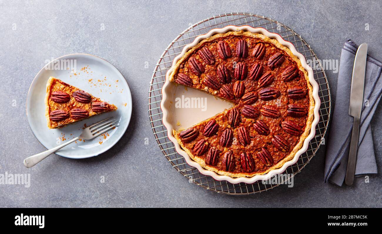 Pecan nuts pie, on a cooling rack. Grey background. Top view. Stock Photo