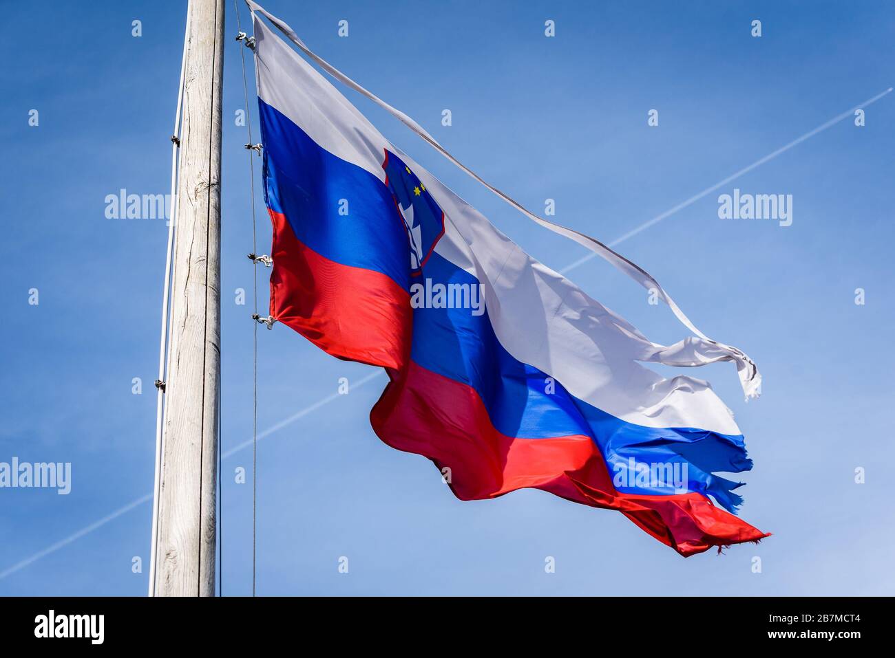 Torn and worn out Slovenian flag waving in the wind. Damaged, worn out