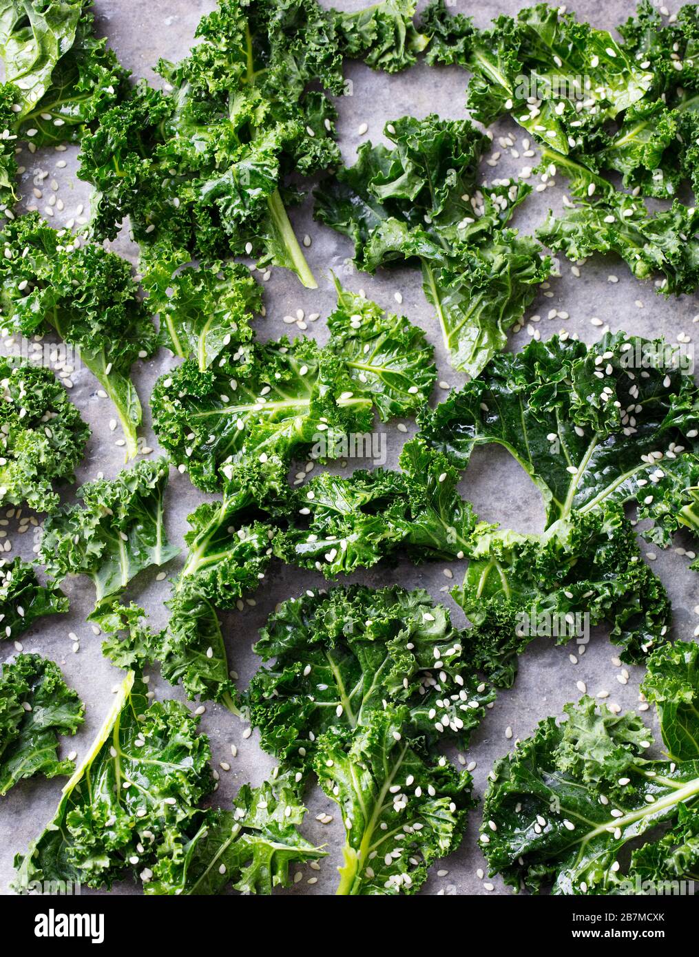 Raw kale leaves on a parchment paper, chips cooking process. Top view