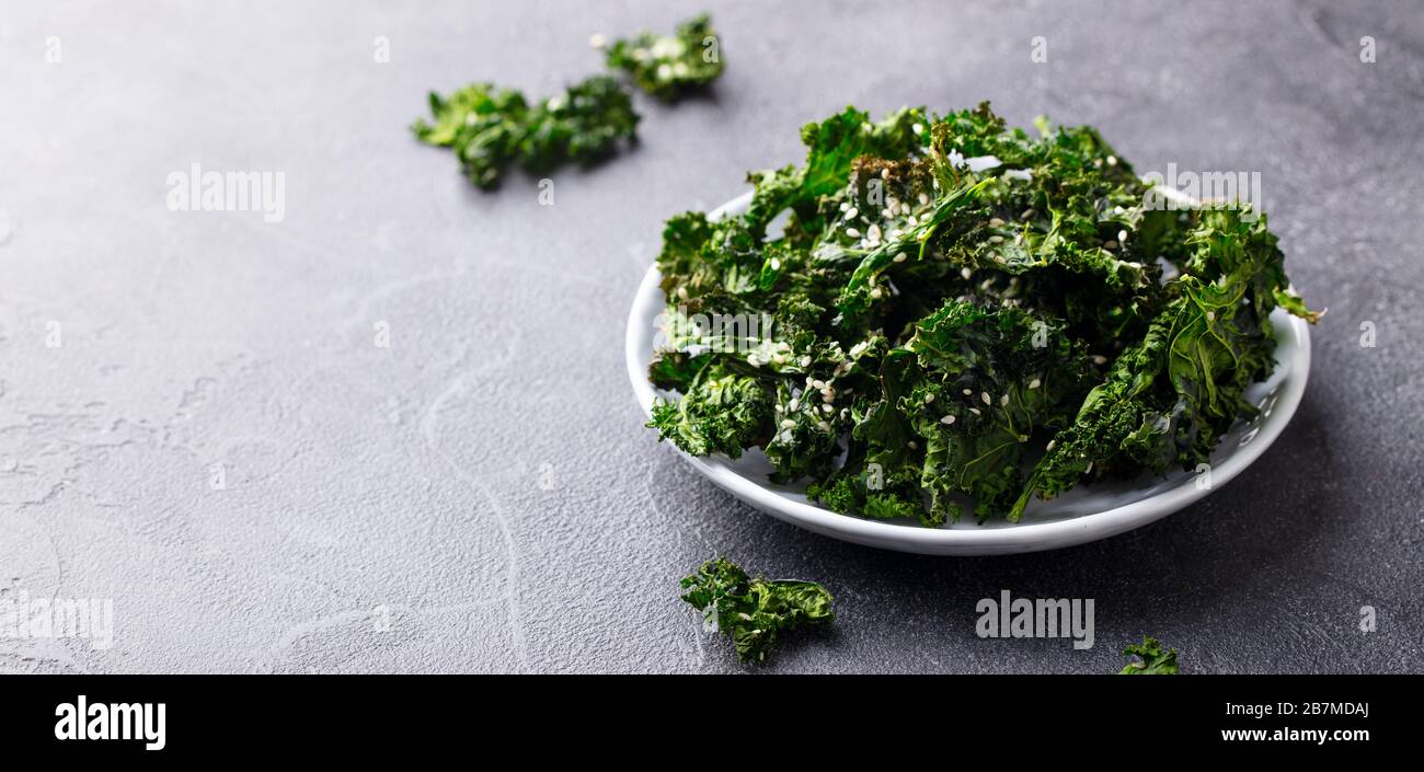 Kale chips, healthy snack on a plate. Grey background. Copy space. Stock Photo