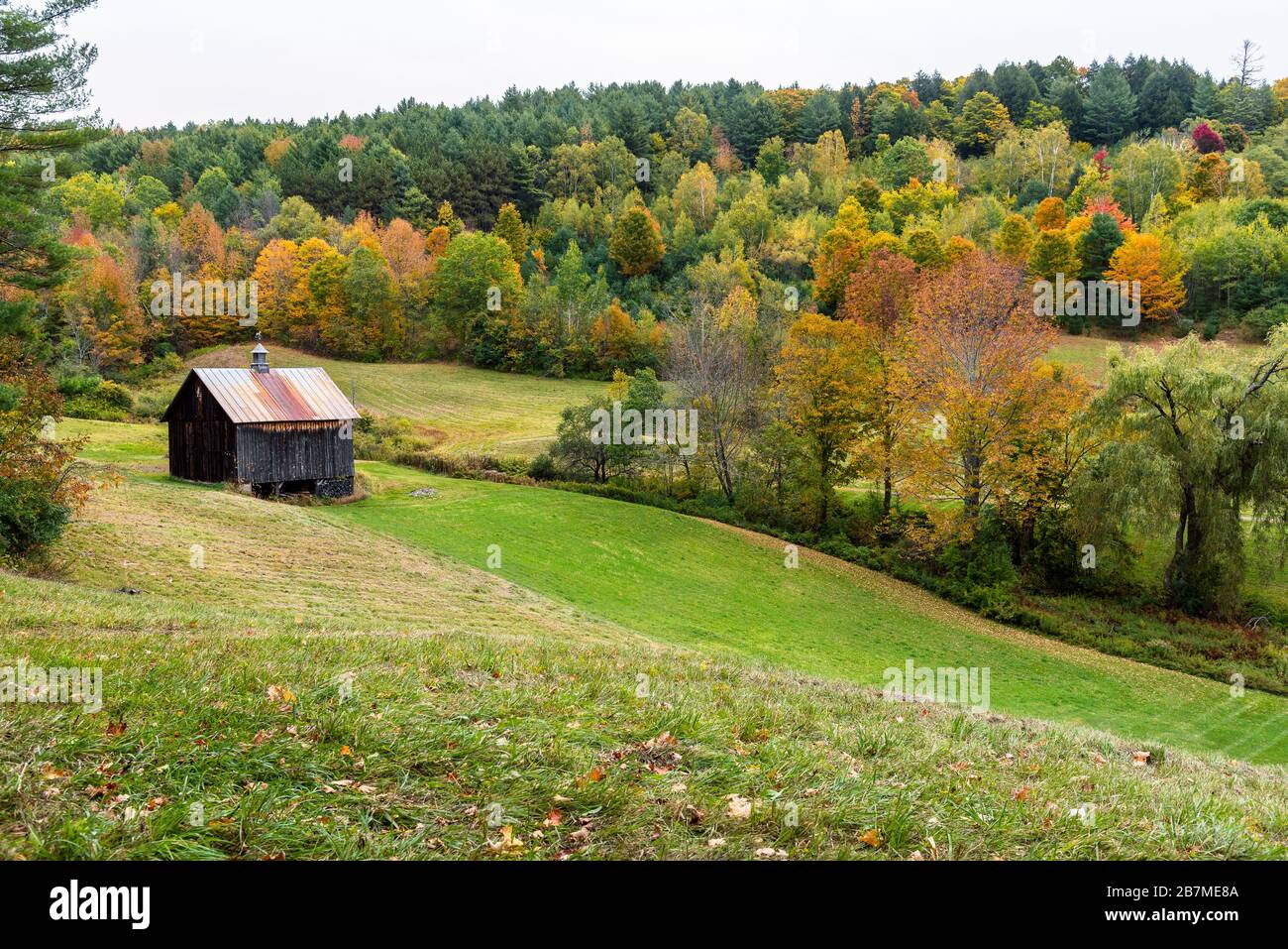 Traditional wooden barn with a metal roof in a rolling rural landscape ...