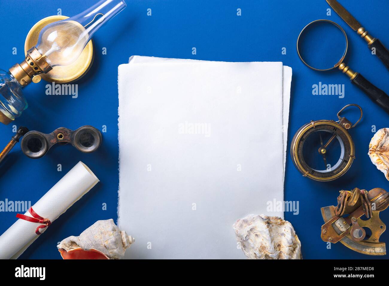 Old fashioned flat lay with retro travel, vacation accessories on blue background. Magnifying glass, compass, sheets, envelope, binoculars. Vintage style, steampunk, gaslight concept. Copyspace. Stock Photo