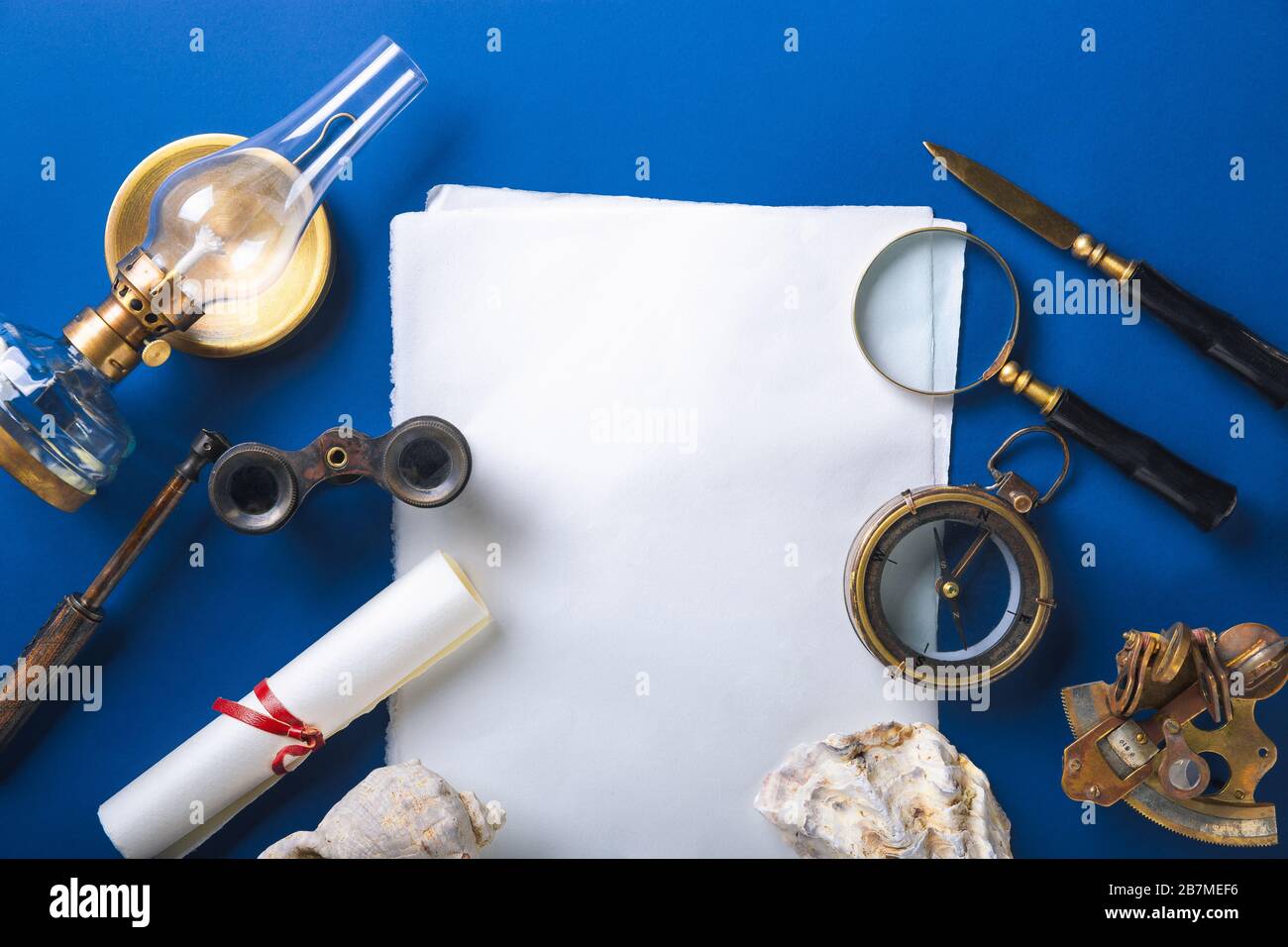 Old fashioned flat lay with retro travel, vacation accessories on blue background. Magnifying glass, compass, sheets, envelope, binoculars. Vintage style, steampunk, gaslight concept. Copyspace. Stock Photo