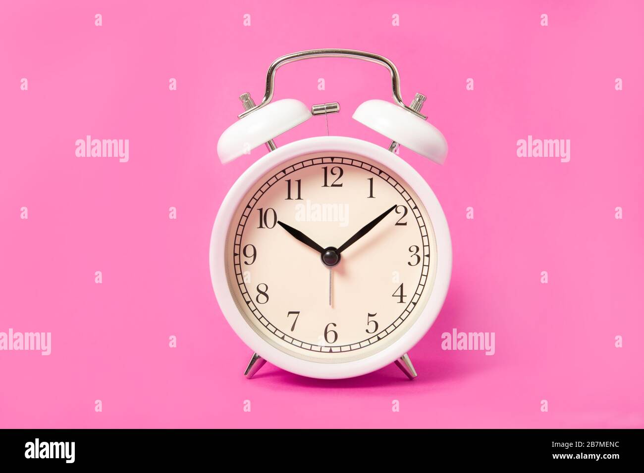 White alarm clock on a pink background. Stock Photo