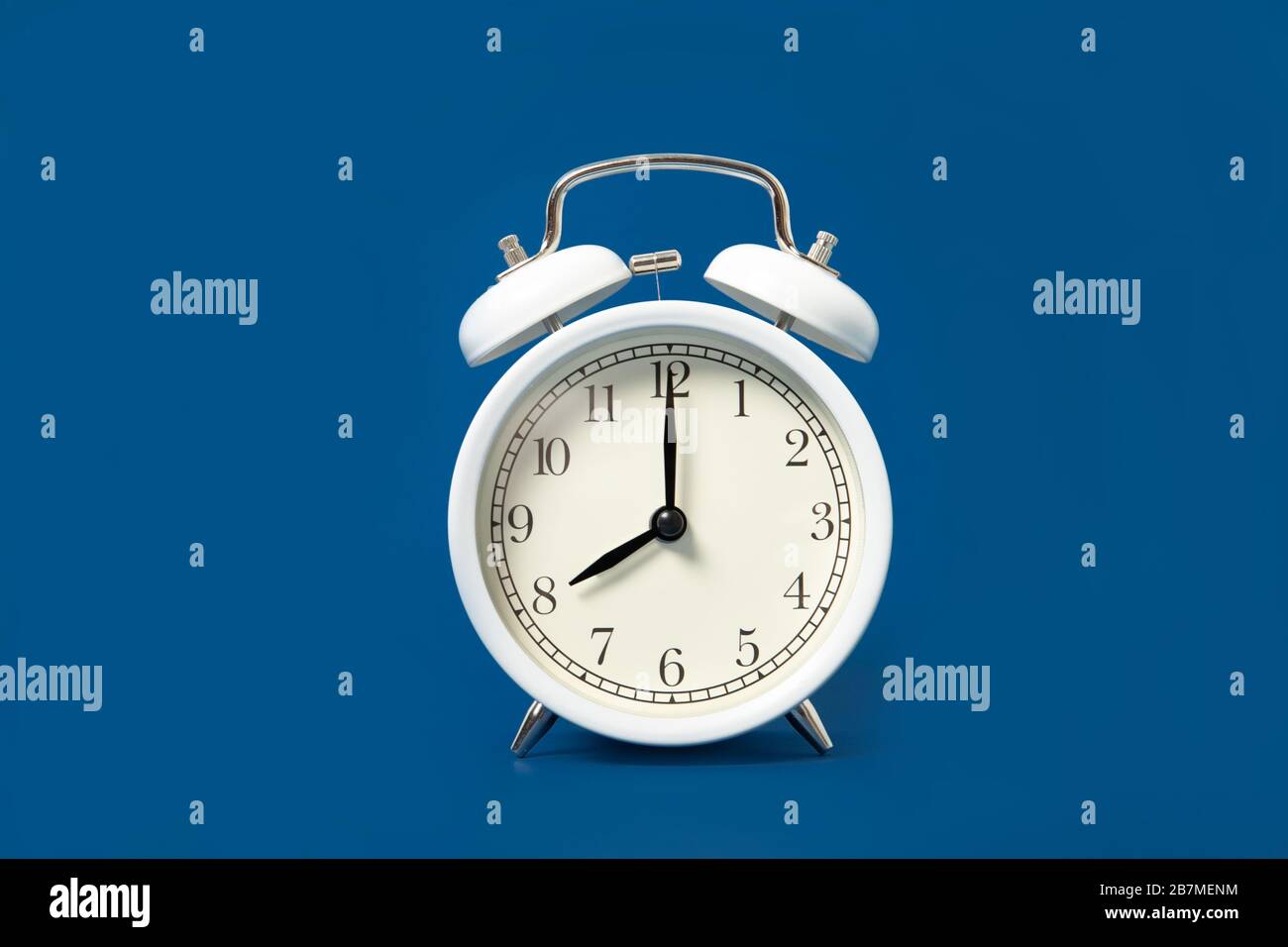 White alarm clock on a blue background. Place for text Stock Photo