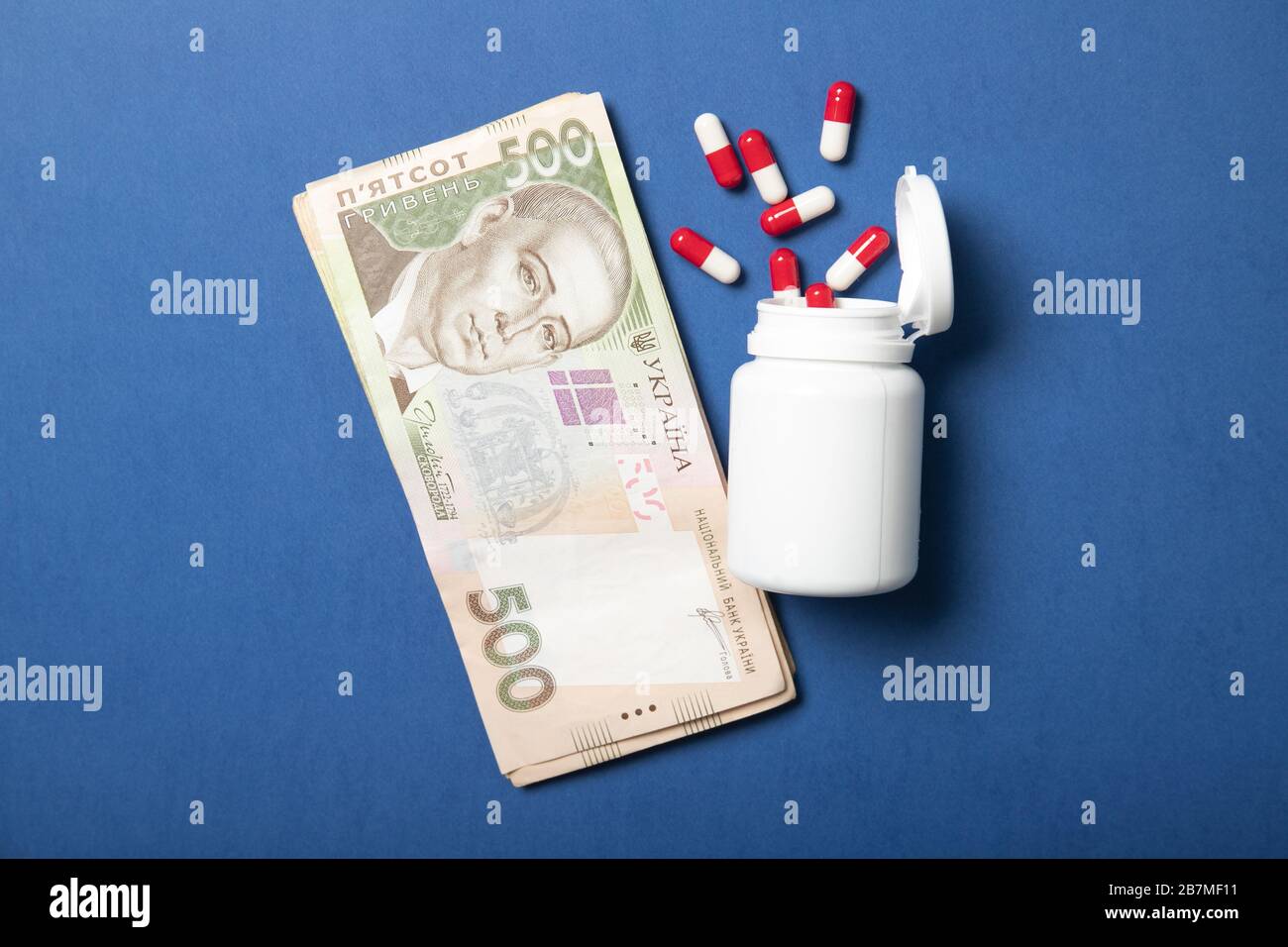 Jar with pills on a blue background. The concept of medicine and health. Higher drug prices. Politics and Health. Ukrainian hryvnia Stock Photo