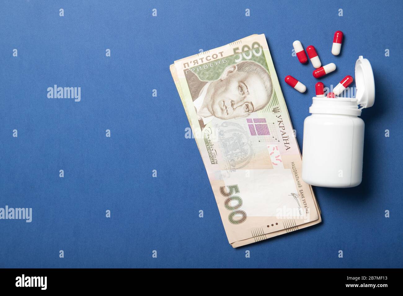 Jar with pills on a blue background. The concept of medicine and health. Higher drug prices. Politics and Health. Ukrainian hryvnia Stock Photo