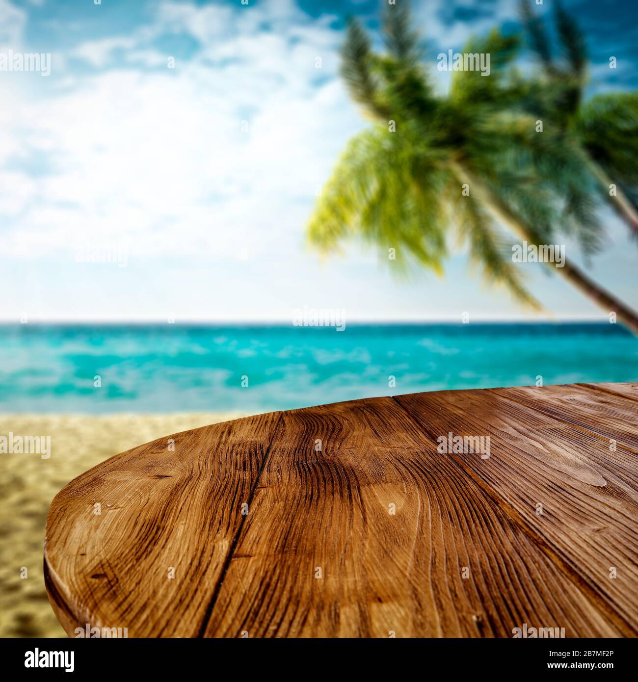 Table background with space for your decoration. Blurred background of beach with green coco palms. Sunny day with blue sky and sunlight. Summer time. Stock Photo