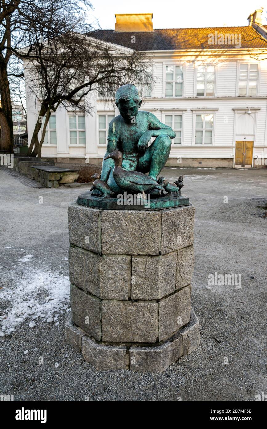 A small bronze statue of a sitting boy and ducks family in Stavanger city park, Norway, December 2017 Stock Photo