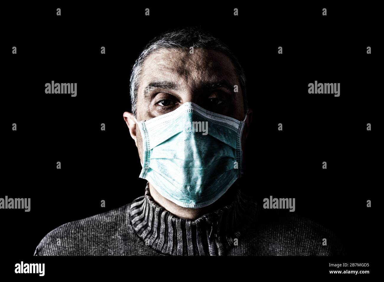 Man with surgical mask. Pandemic or epidemic and scary, fear or danger concept. Protection for biohazard like COVID-19 aka Coronavirus. Black Backgrou Stock Photo