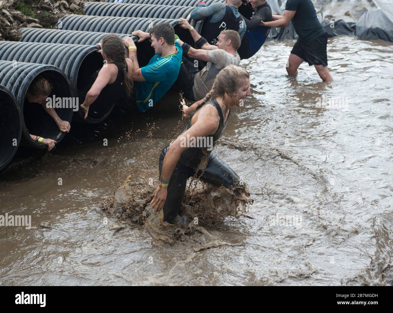 A soaking wet participant exits the water at the Shawshanked obstacle at a Tough Mudder event Stock Photo
