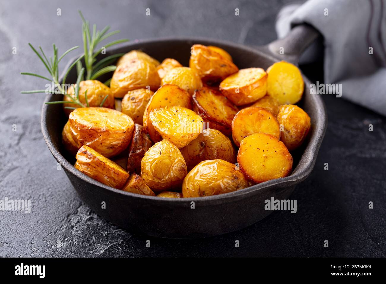 Roasted baby potatoes in iron skillet. Dark grey background. Close up. Stock Photo