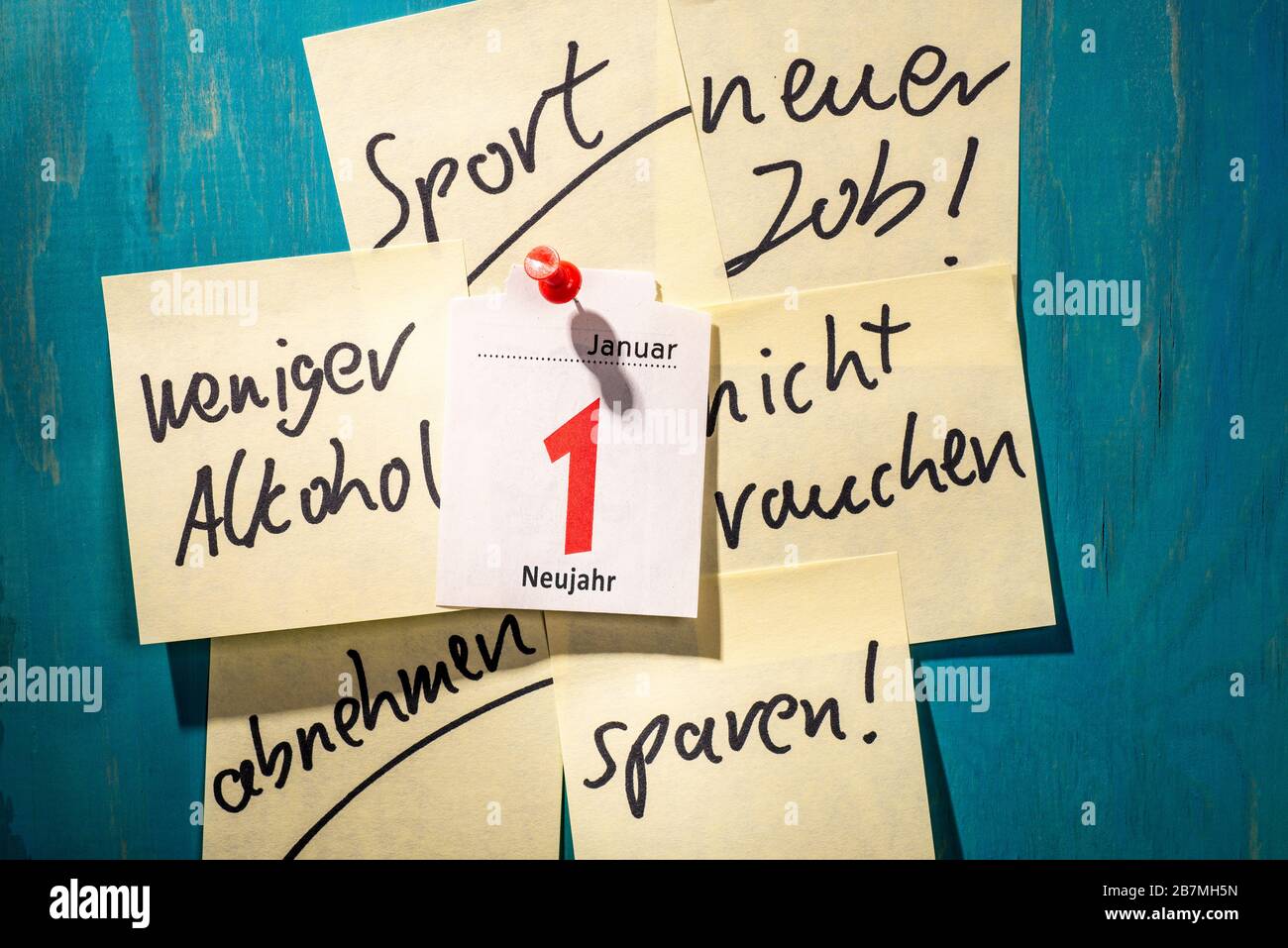 Note with good resolutions on a wall with a calendar page showing the first of January. Stock Photo