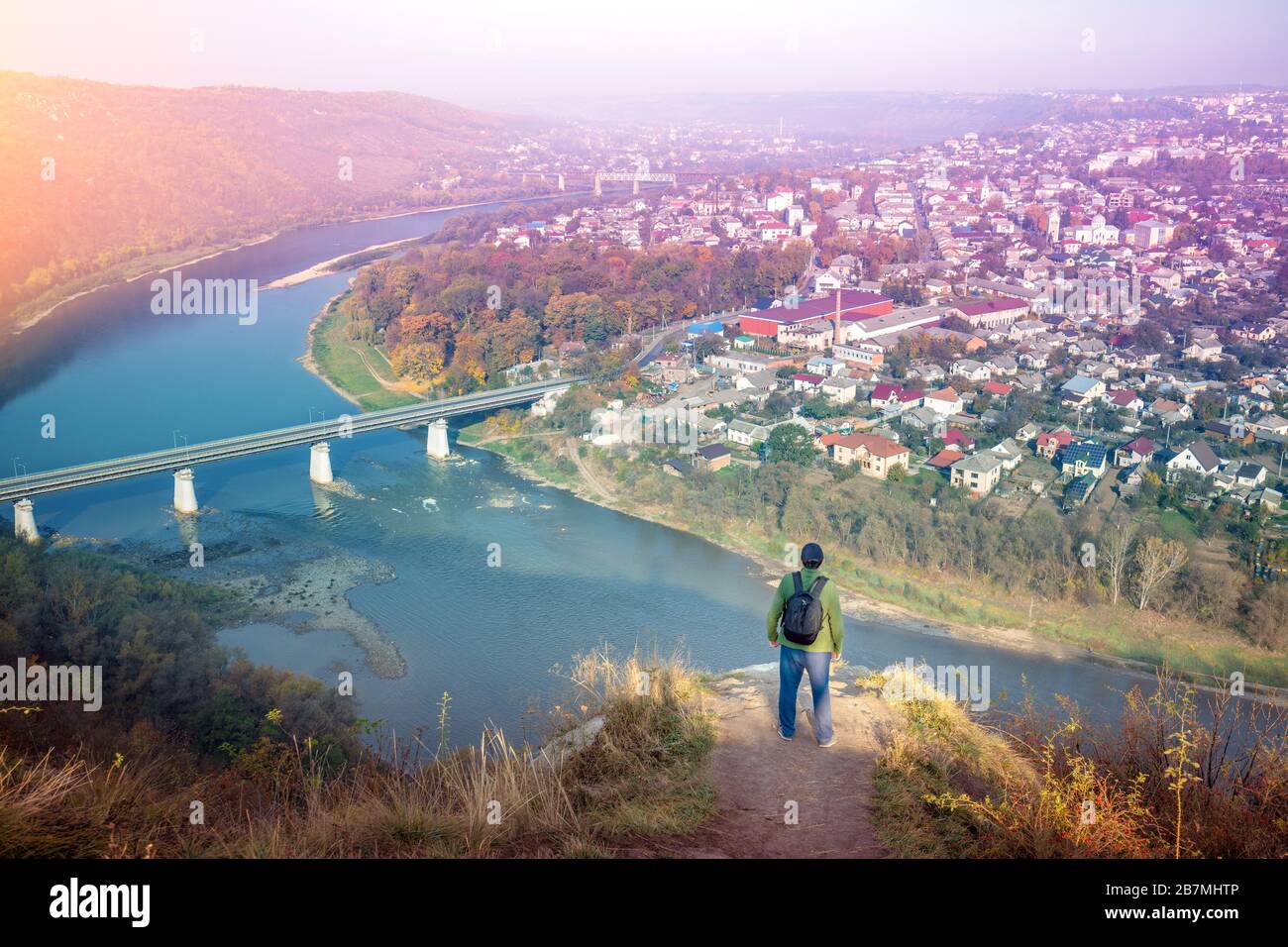 A man stands on a hill and looks at a fantastic view of the winding Dniester River at dawn in the fall. Dniester Canyon National Park, Zalishchyky tow Stock Photo