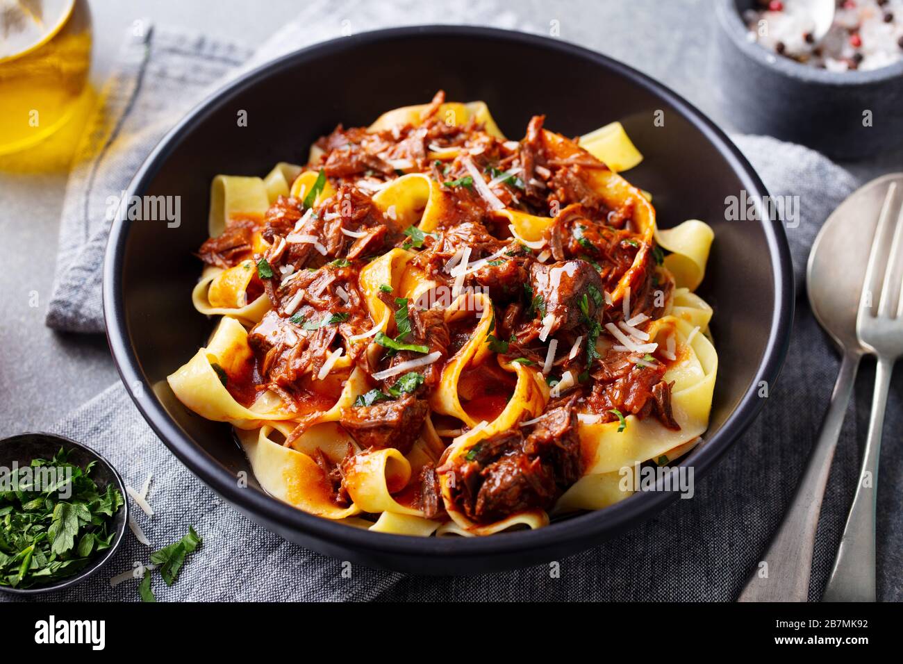 Pasta pappardelle with beef ragout sauce in black bowl. Grey background. Close up. Stock Photo