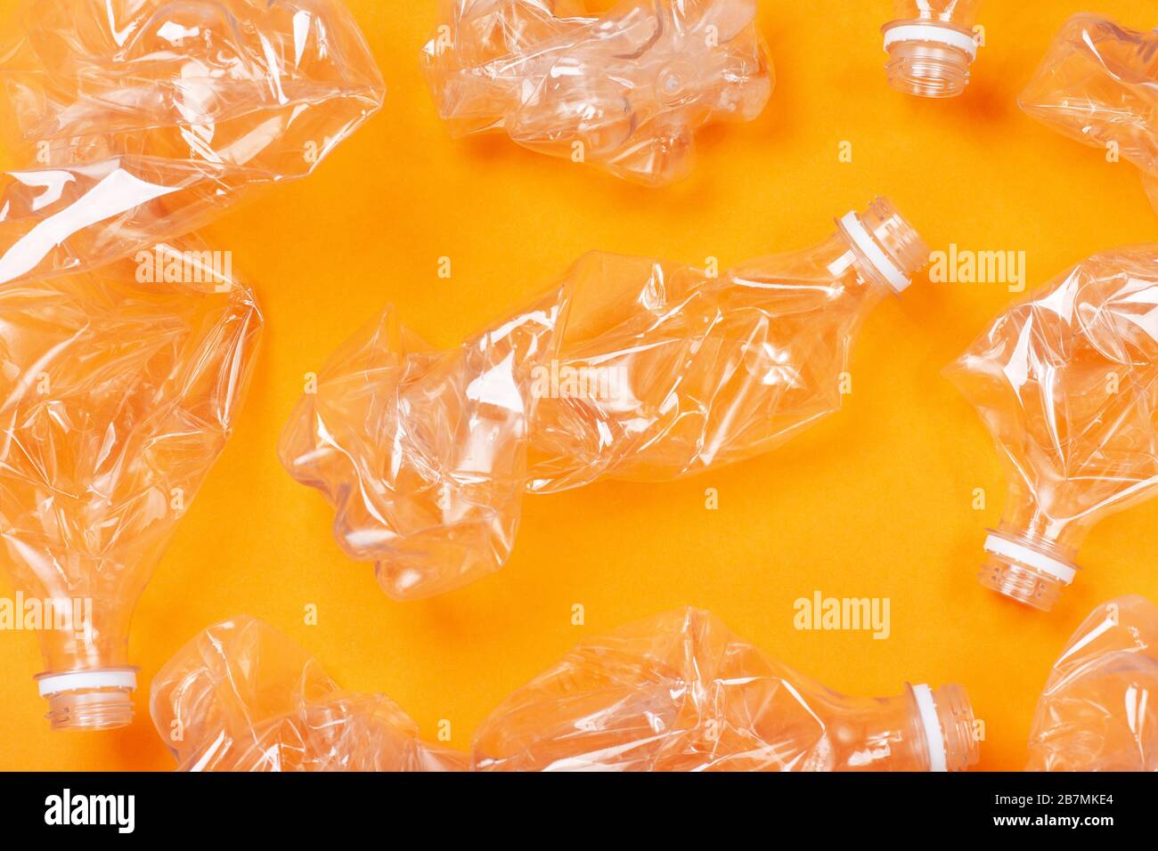 A lot of used plastic bottles on orange background. The concept of pollution of the planet and the oceans with plastic waste. Stock Photo