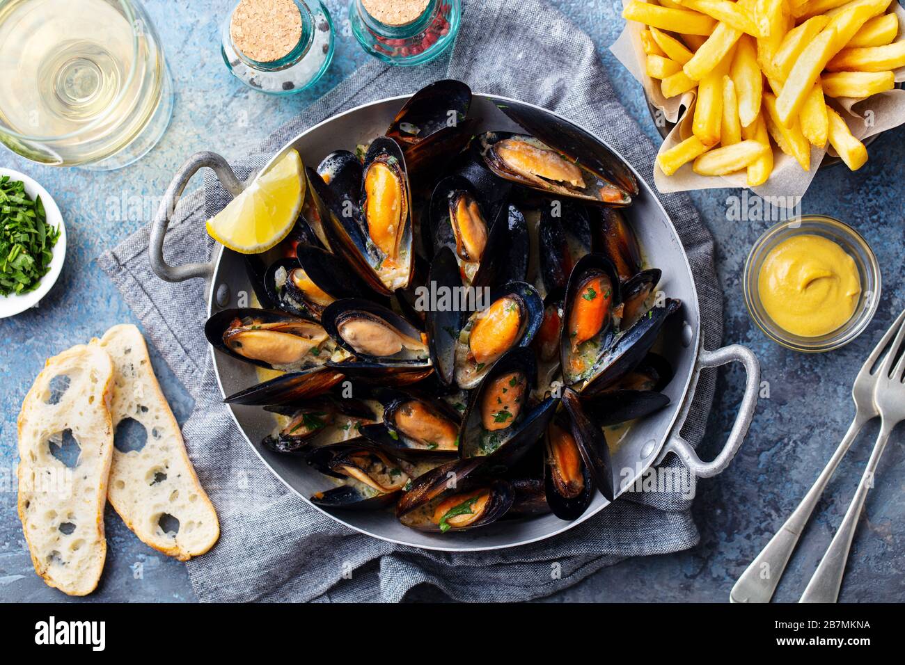 Mussels with french fries and white wine in cooking pan. Grey background. Close up. Top view. Stock Photo